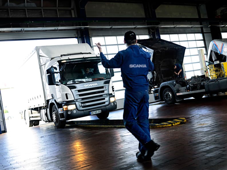 Mekaniker geleider inn en lastebil på Scania-verksted